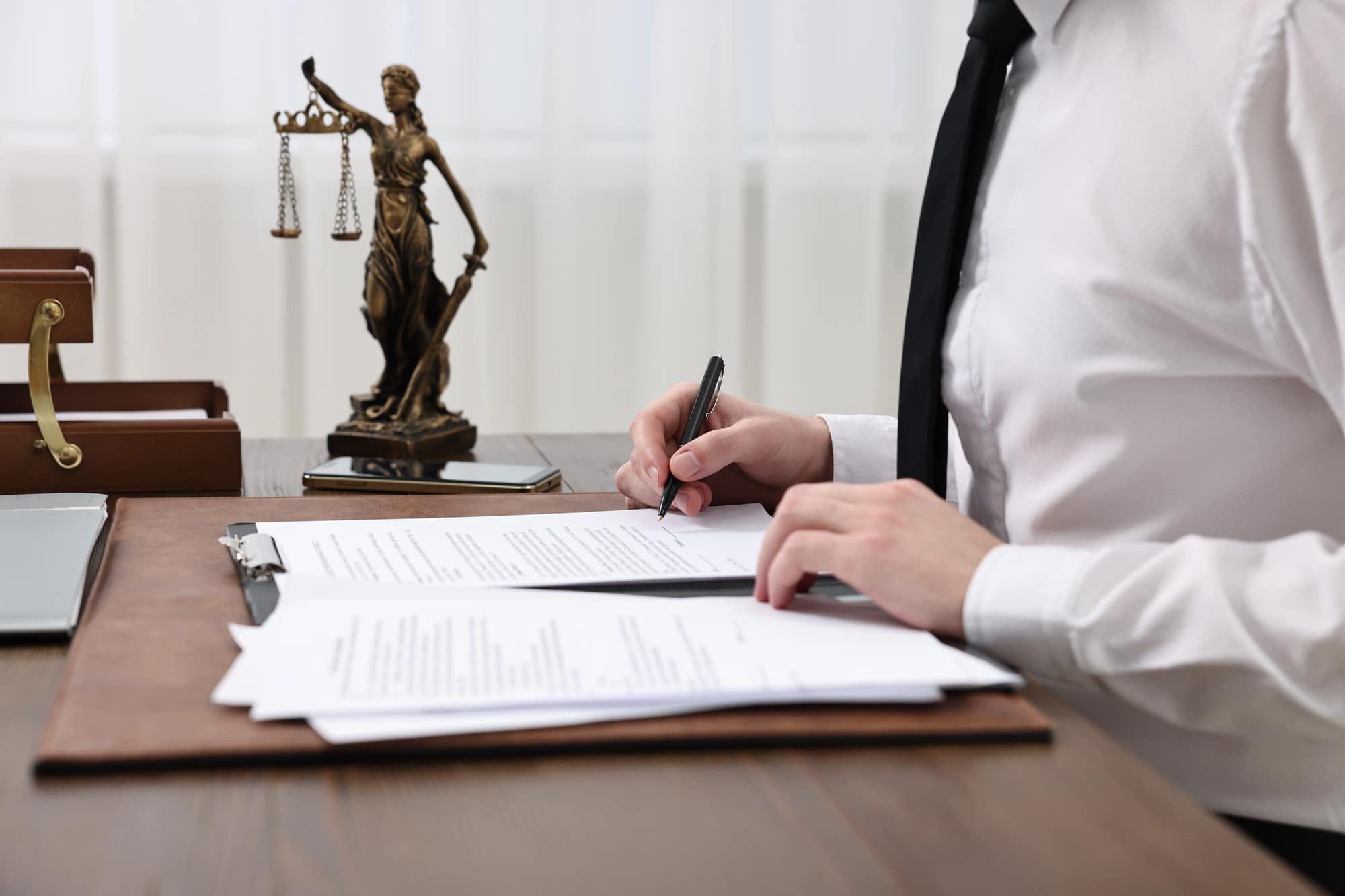 Lawyer reviewing legal documents at wooden desk workspace